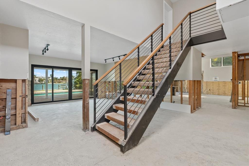 An unfinished room features a modern staircase with metal railings and a view of water — 847 FREELING DRIVE, SARASOTA, FL
