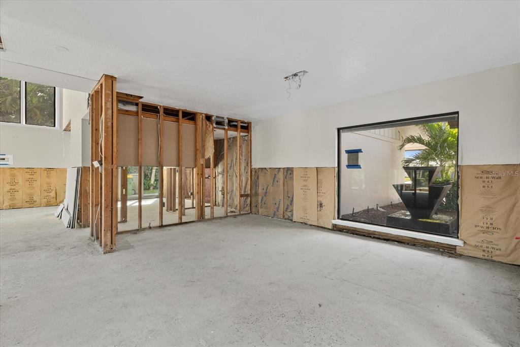 An unfinished room with exposed wall studs, concrete flooring, and a large window overlooking landscaping — 847 FREELING DRIVE, SARASOTA, FL