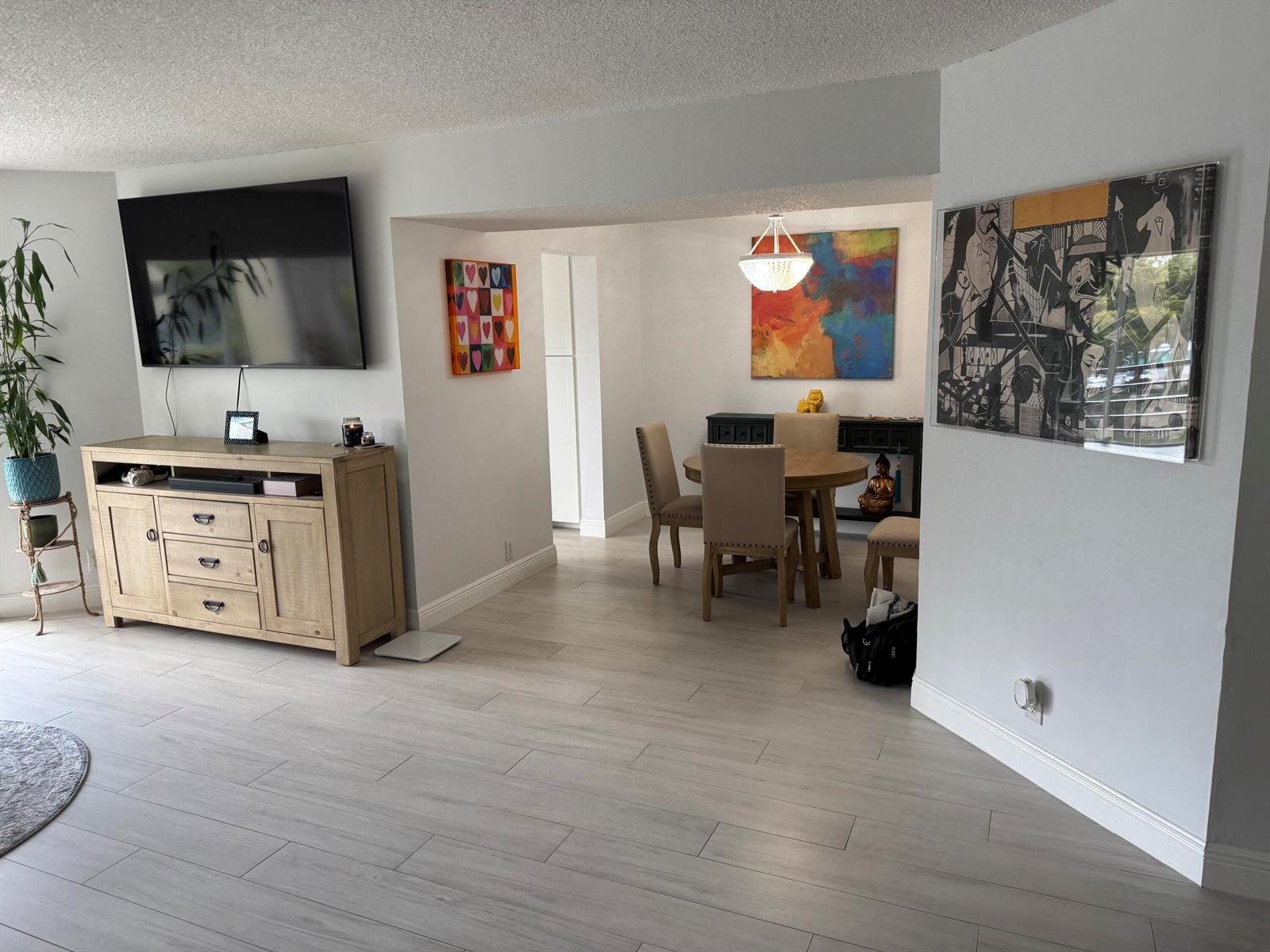 A living room with light wood flooring leads to a dining area with a chandelier — 3590 Via # 312, Lake Worth FL 33467, LAKE WORTH, FL