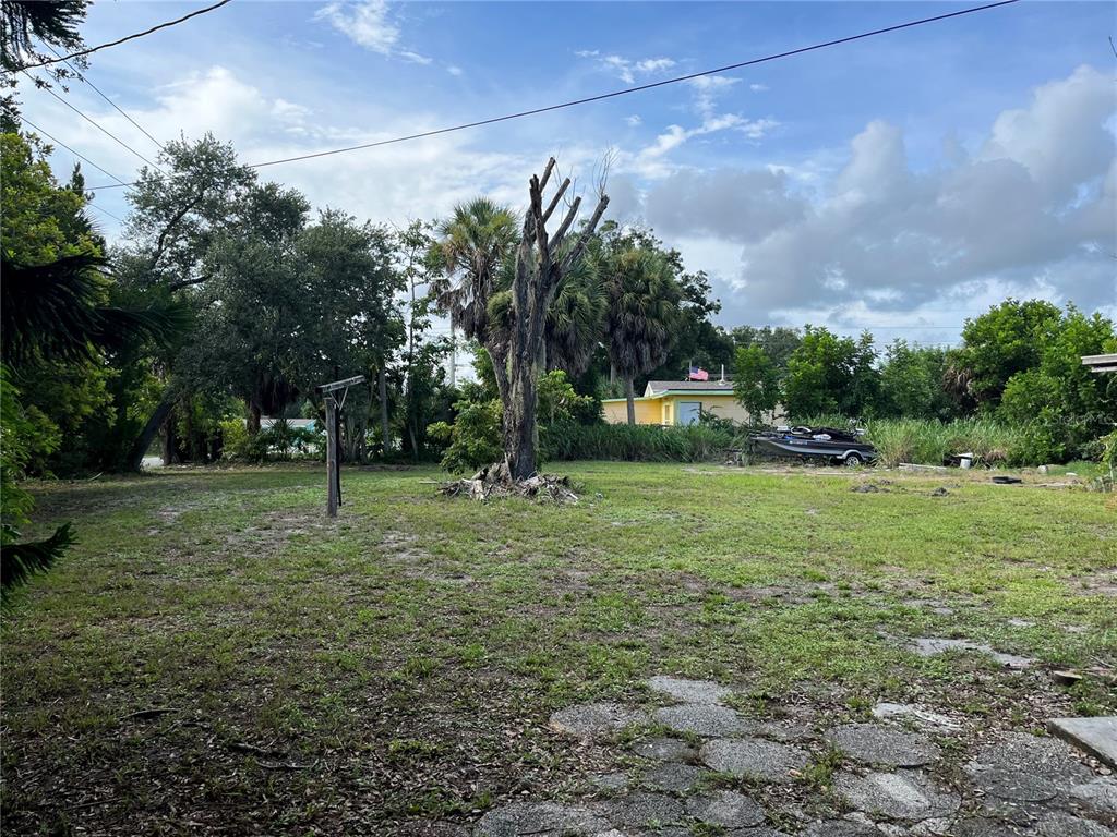 A grassy, partially shaded lot features a large, bare tree and a distant yellow house — 903 ANDERSON ROAD, NOKOMIS, FL
