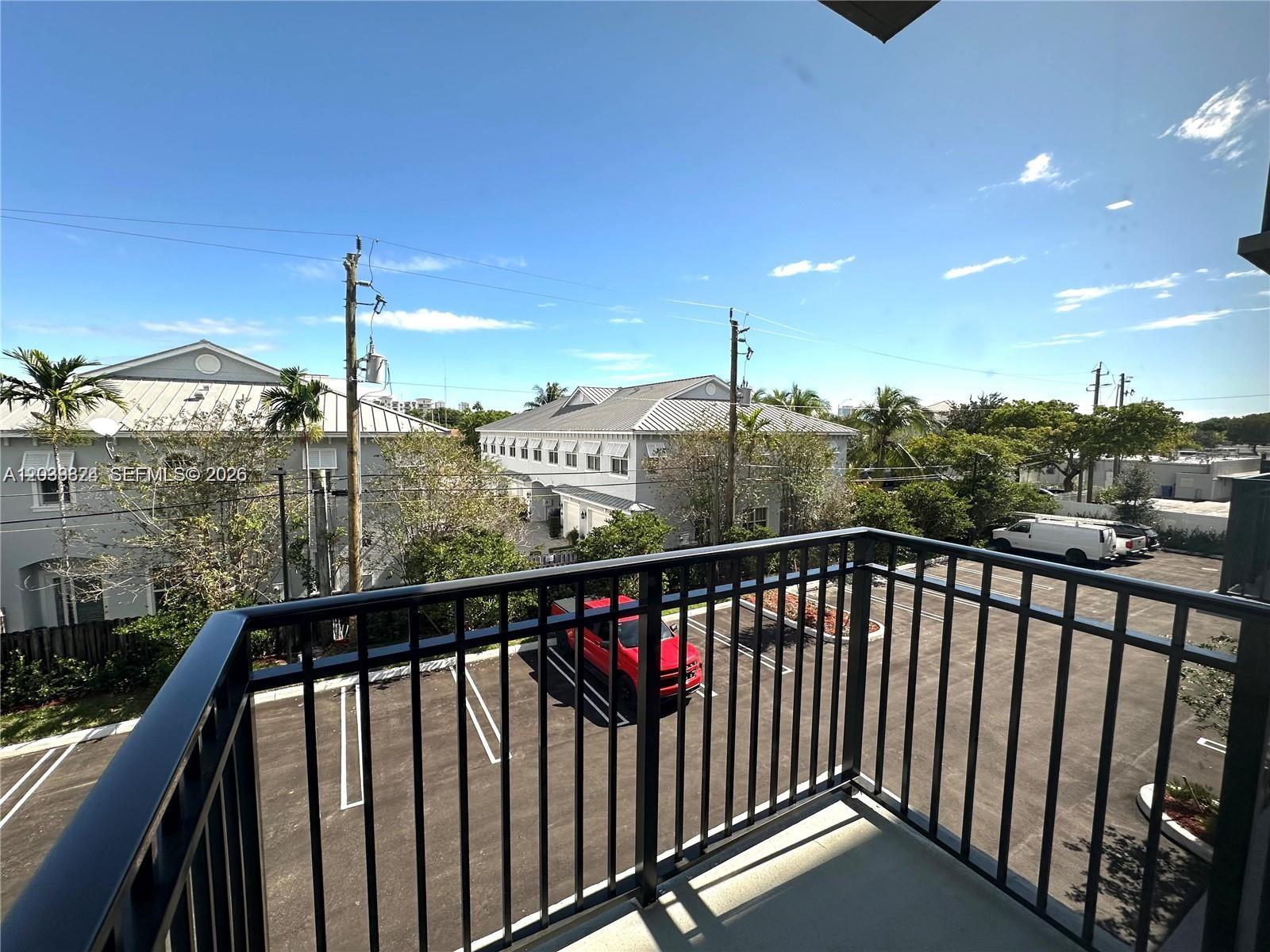 A balcony with a black metal railing overlooks a parking lot and nearby buildings — 20 NE 19th Ave # 213, Pompano Beach FL 33060, POMPANO BEACH, FL