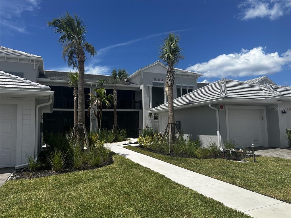 A two-story residential building with a concrete walkway, palm trees, and attached garages — 14251 HERITAGE LANDING BOULEVARD UNIT 1723, PUNTA GORDA, FL