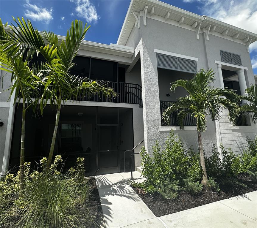 A two-story building exterior features a screened-in ground floor patio, a balcony, and palm trees — 14251 HERITAGE LANDING BOULEVARD UNIT 1723, PUNTA GORDA, FL
