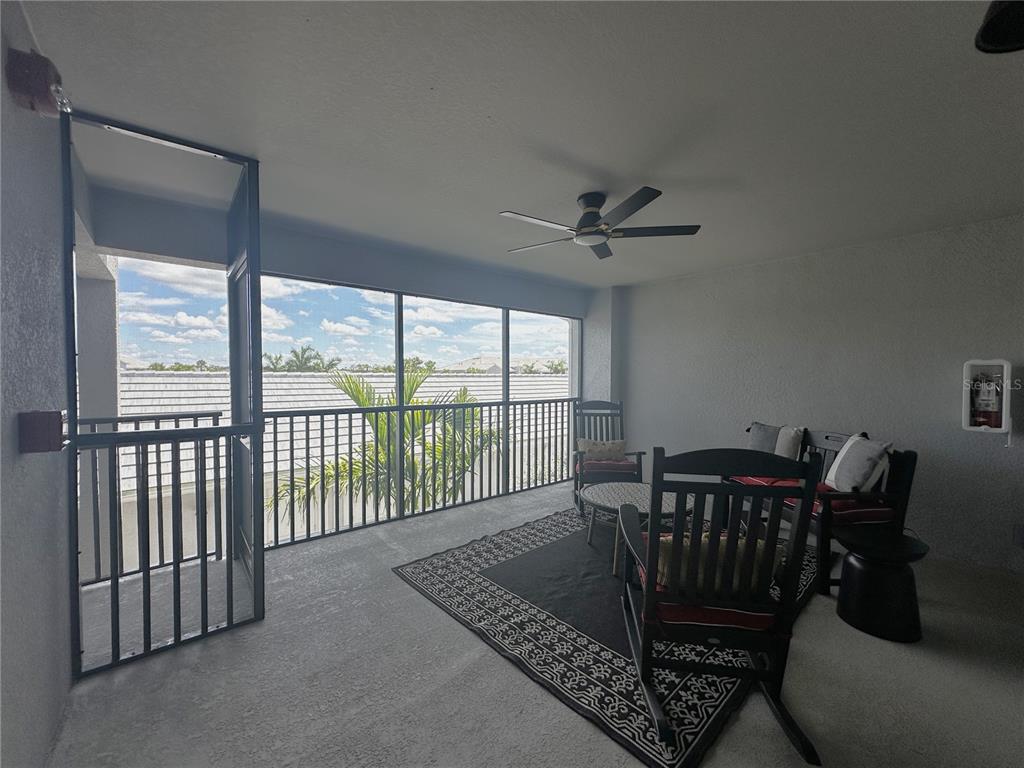 A screened-in balcony features a ceiling fan, outdoor furniture, and a view of rooftops — 14251 HERITAGE LANDING BOULEVARD UNIT 1723, PUNTA GORDA, FL