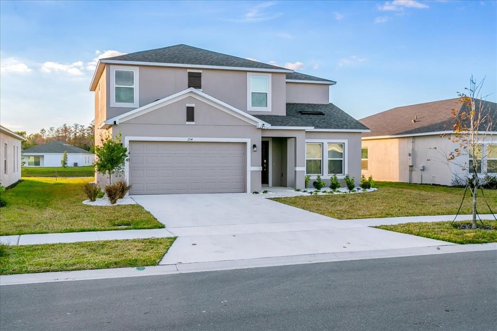 A two-story suburban house with a beige stucco exterior and a two-car garage — 254 AMBER WAY, KISSIMMEE, FL