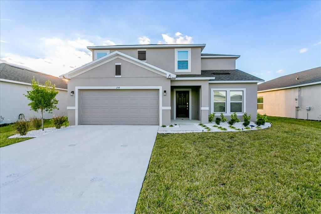 A two-story suburban house with a gray stucco exterior, a two-car garage, and a front lawn — 254 AMBER WAY, KISSIMMEE, FL