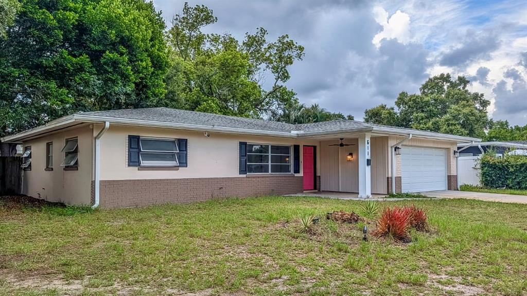 A single-story house with a white garage door, tan brick base, and light-colored siding — 611 PATRICIA AVENUE, DUNEDIN, FL
