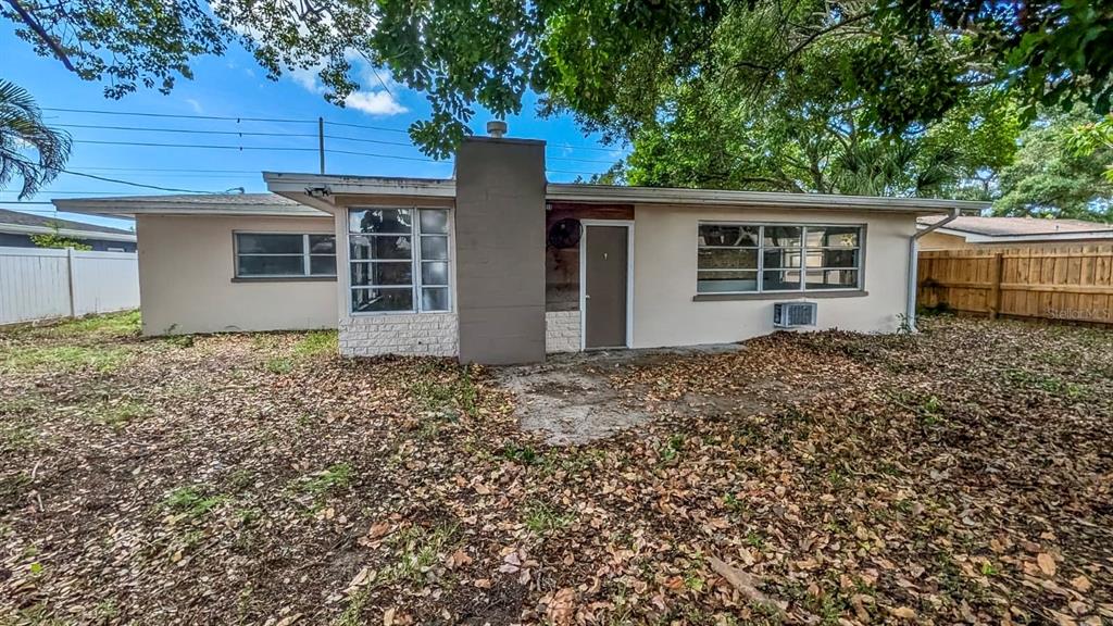 A single-story house with a beige exterior, brick base, pink front door, and attached garage — 611 PATRICIA AVENUE, DUNEDIN, FL