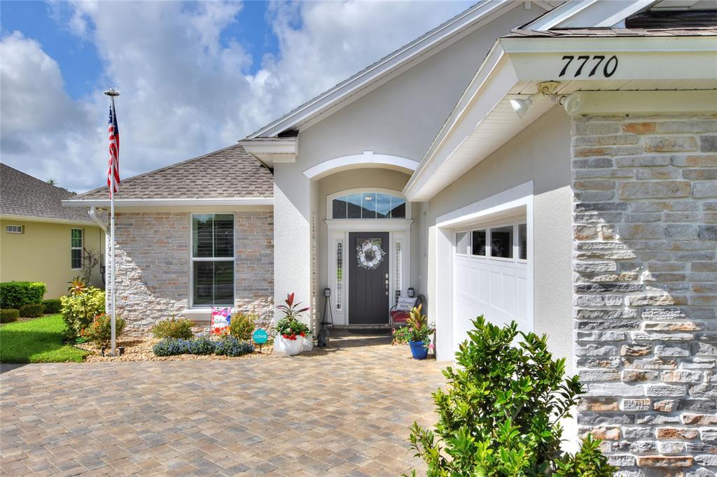 The exterior of a house features a stone facade, a paved driveway, and a front entrance — 7770 LAKE JAMES BOULEVARD, LAKELAND, FL