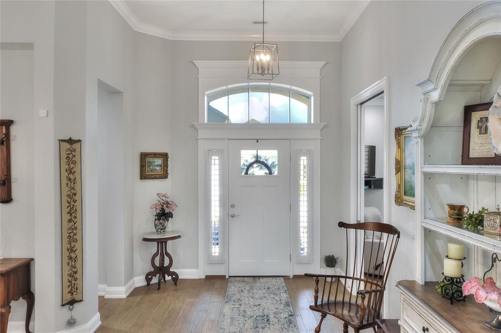 A bright entryway features a white front door, transom window, wood flooring, and wooden chair — 7770 LAKE JAMES BOULEVARD, LAKELAND, FL
