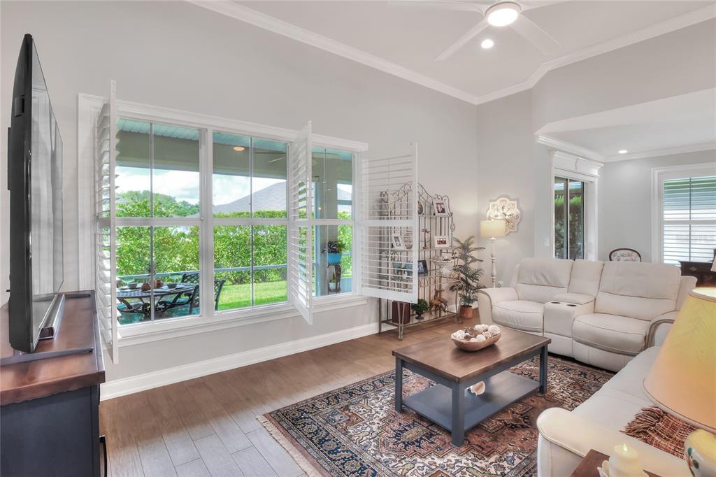 A living room features white leather sofas, a wooden coffee table, and large plantation shutters — 7770 LAKE JAMES BOULEVARD, LAKELAND, FL