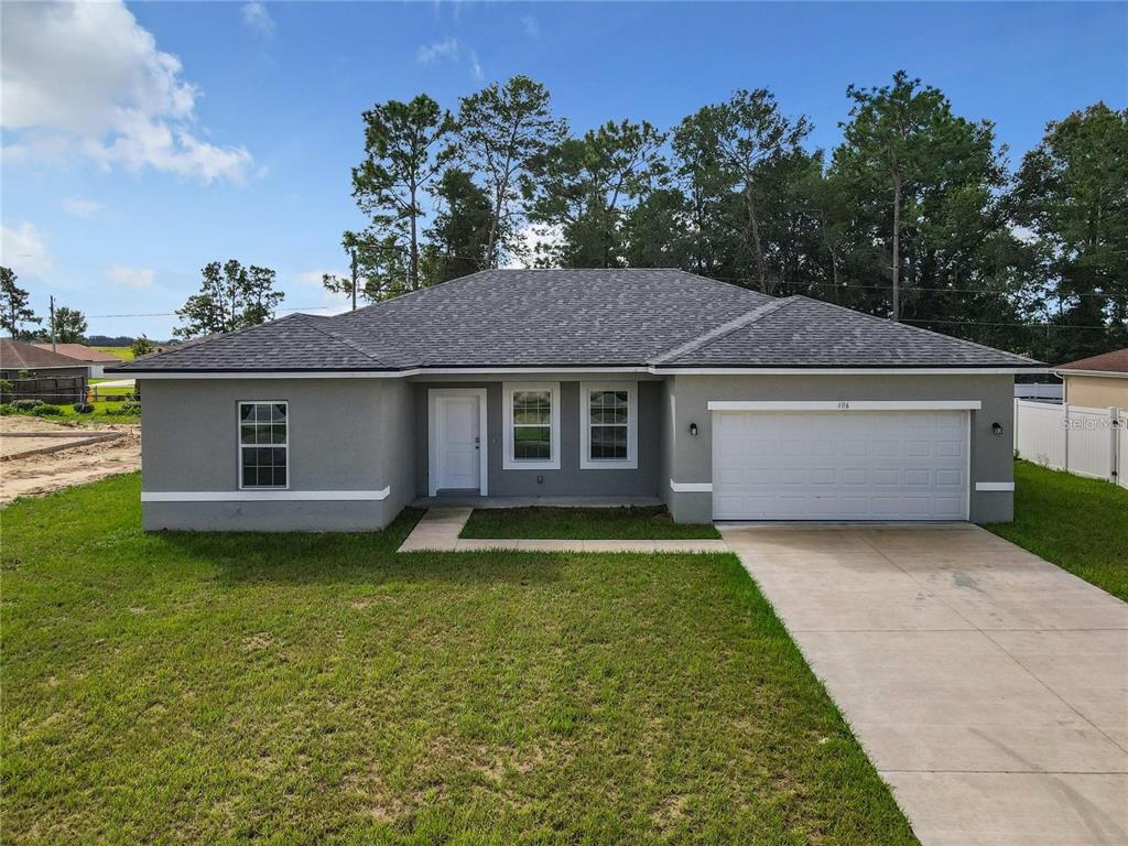 A single-story gray house with a white garage door and a concrete driveway — 406 MARION OAKS TRAIL, OCALA, FL