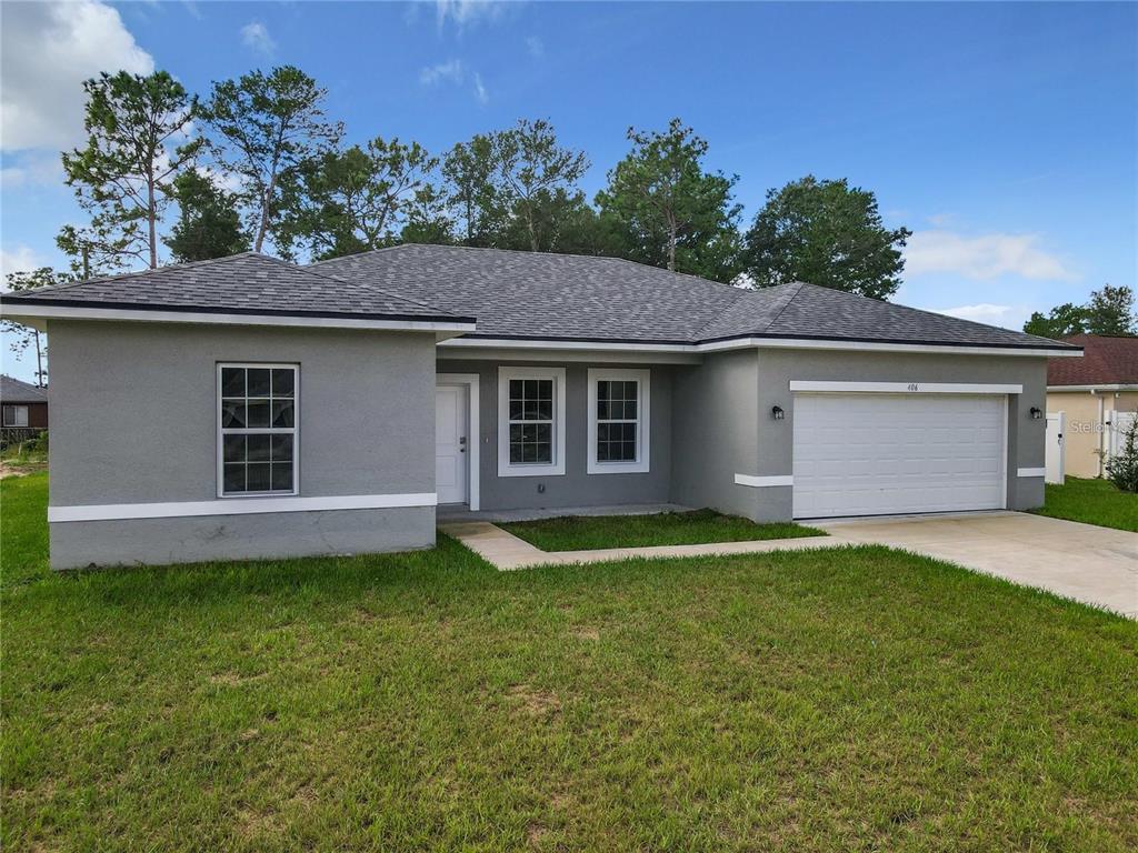 A single-story gray house with a white garage door and a concrete walkway — 406 MARION OAKS TRAIL, OCALA, FL