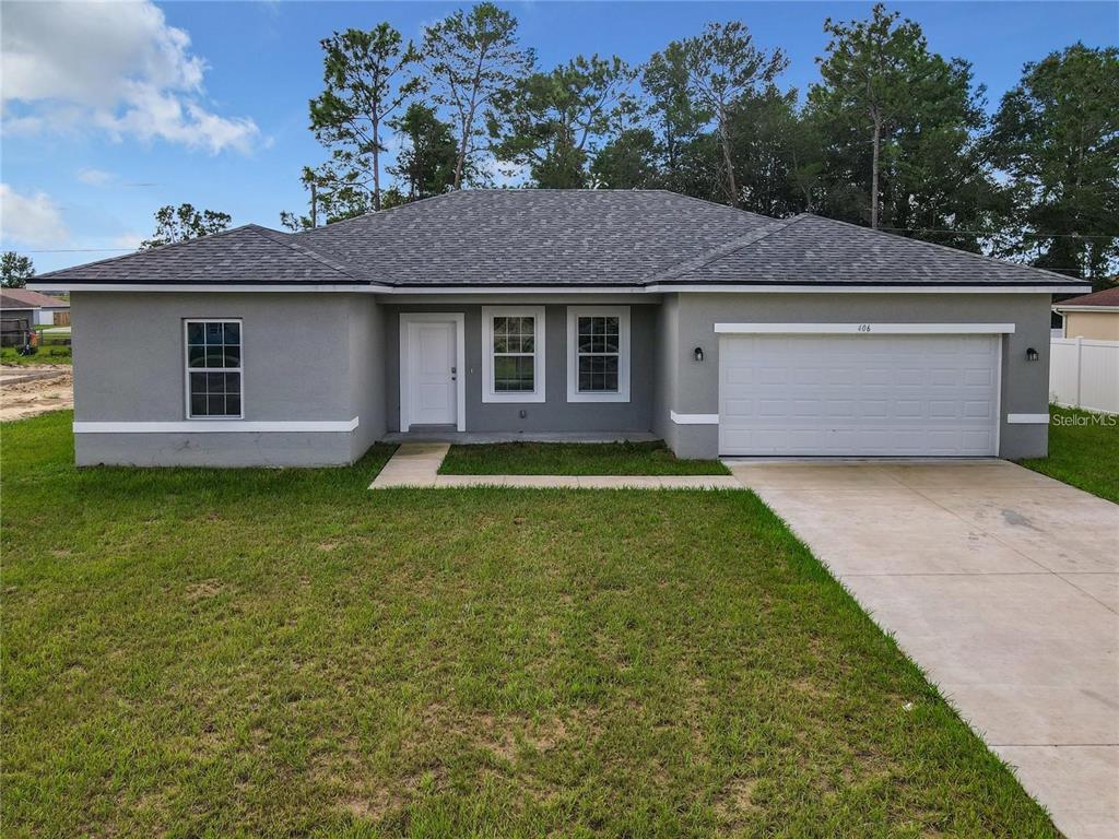 A single-story gray house with a white garage door and a concrete driveway — 406 MARION OAKS TRAIL, OCALA, FL