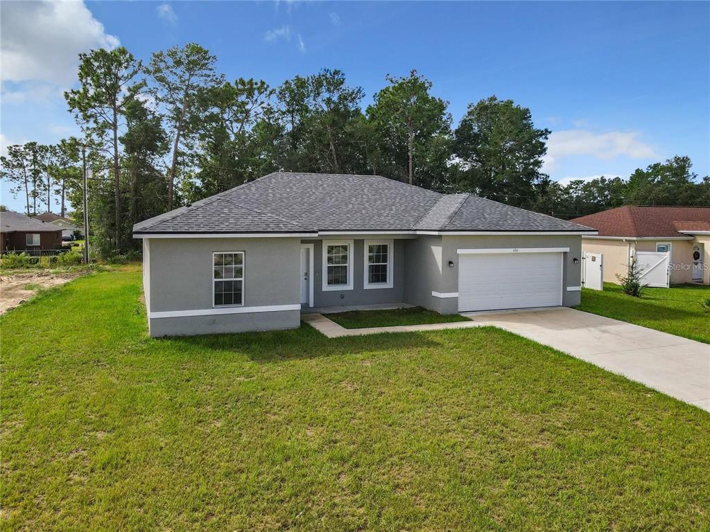 A single-story gray house with a white garage door and a shingled roof — 406 MARION OAKS TRAIL, OCALA, FL