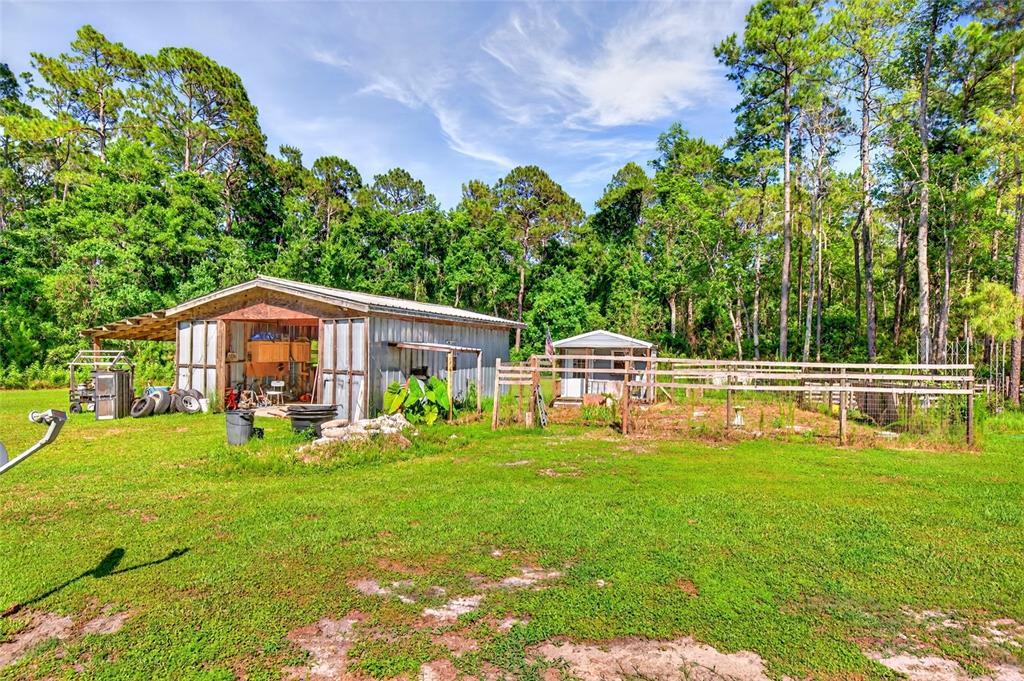 A metal workshop and a small shed sit on a grassy lot near trees — 16240 NE 141ST TERRACE, FORT MC COY, FL
