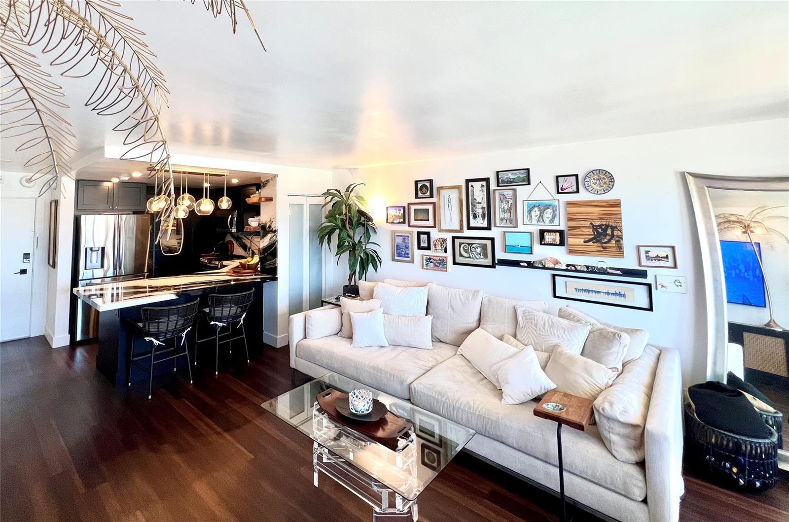 A living room with a beige sofa, gallery wall, and an open kitchen with bar seating — 133 N Pompano Beach Boulevard # 1506, Pompano Beach FL 33062, POMPANO BEACH, FL