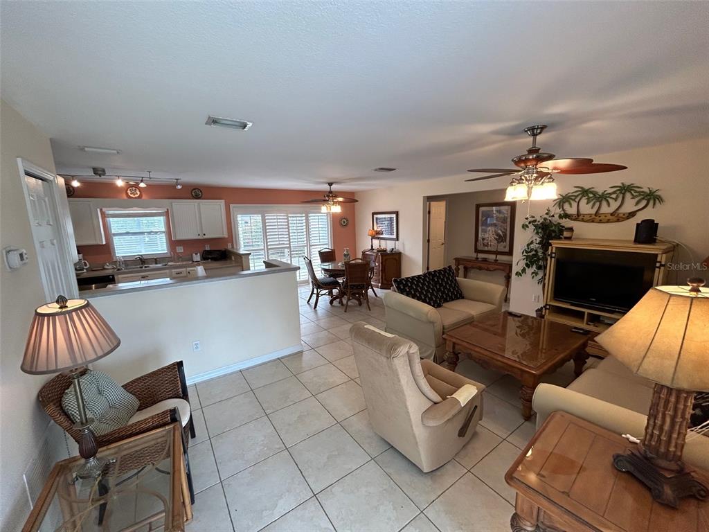 An open-concept living and dining area features tile flooring, a kitchen, and a ceiling fan — 1808 N PENINSULA AVENUE, NEW SMYRNA BEACH, FL