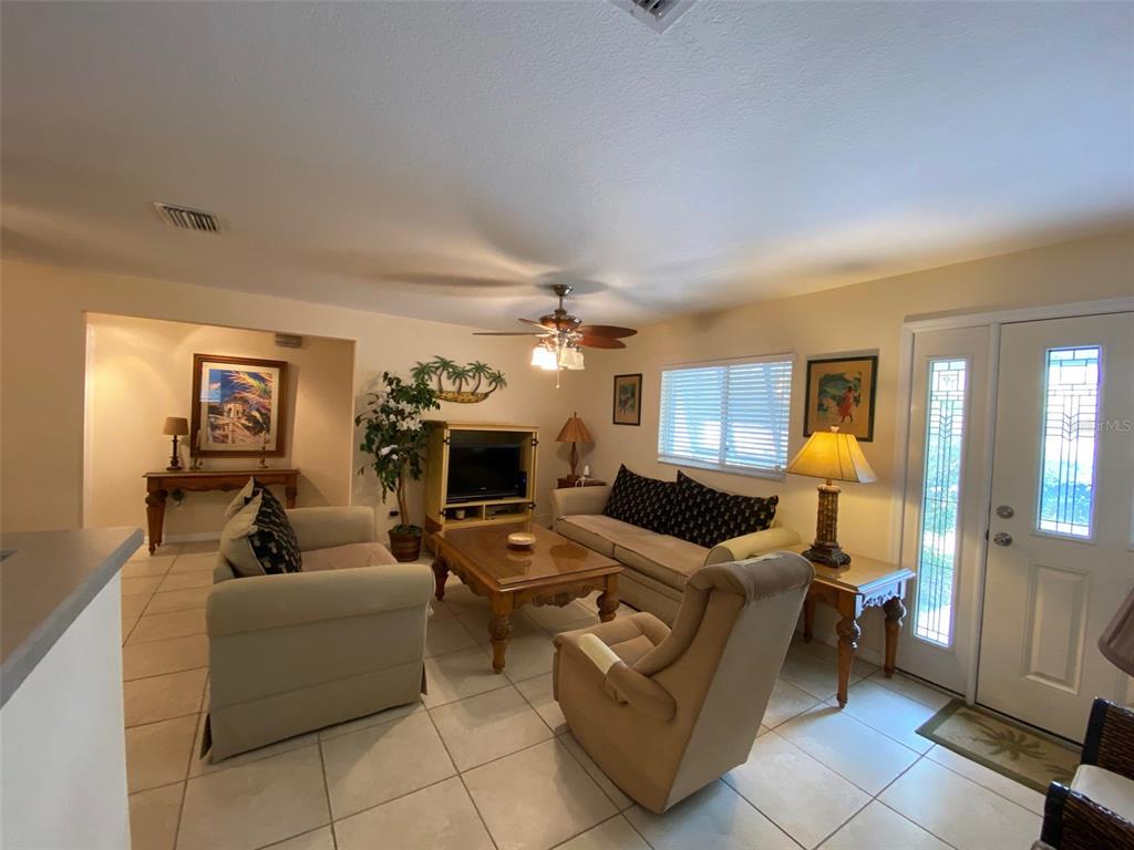 A living room features light tile flooring, a ceiling fan, a sofa, and a recliner — 1808 N PENINSULA AVENUE, NEW SMYRNA BEACH, FL