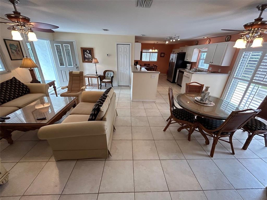 An open-concept living and dining area features tile flooring, ceiling fans, and a kitchen island — 1808 N PENINSULA AVENUE, NEW SMYRNA BEACH, FL