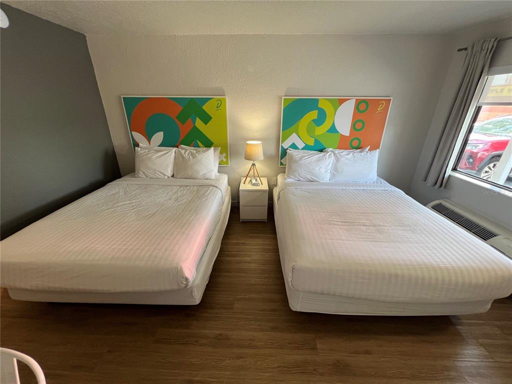 A bedroom features two beds with colorful headboards, a central nightstand, and wood-look flooring — 5367 W IRLO BRONSON MEMORIAL HWY UNIT 1-103, KISSIMMEE, FL