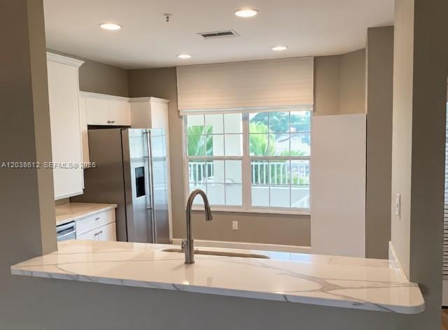 A kitchen features white cabinets, stainless steel appliances, and a marble-look countertop with a sink — 3017 Driftwood Way # 0, Naples FL 34109, NAPLES, FL