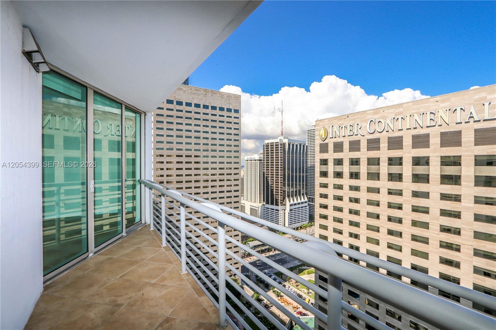 A balcony with tiled flooring and a metal railing overlooks a city skyline — 335 S Biscayne Blvd # 3510, Miami FL 33131, MIAMI, FL