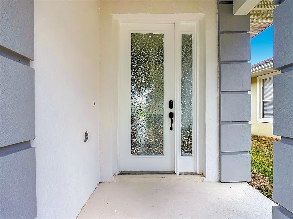 A white front door with textured glass panels is set within a covered entryway — 2944 SUNSET VISTA BOULEVARD, KISSIMMEE, FL