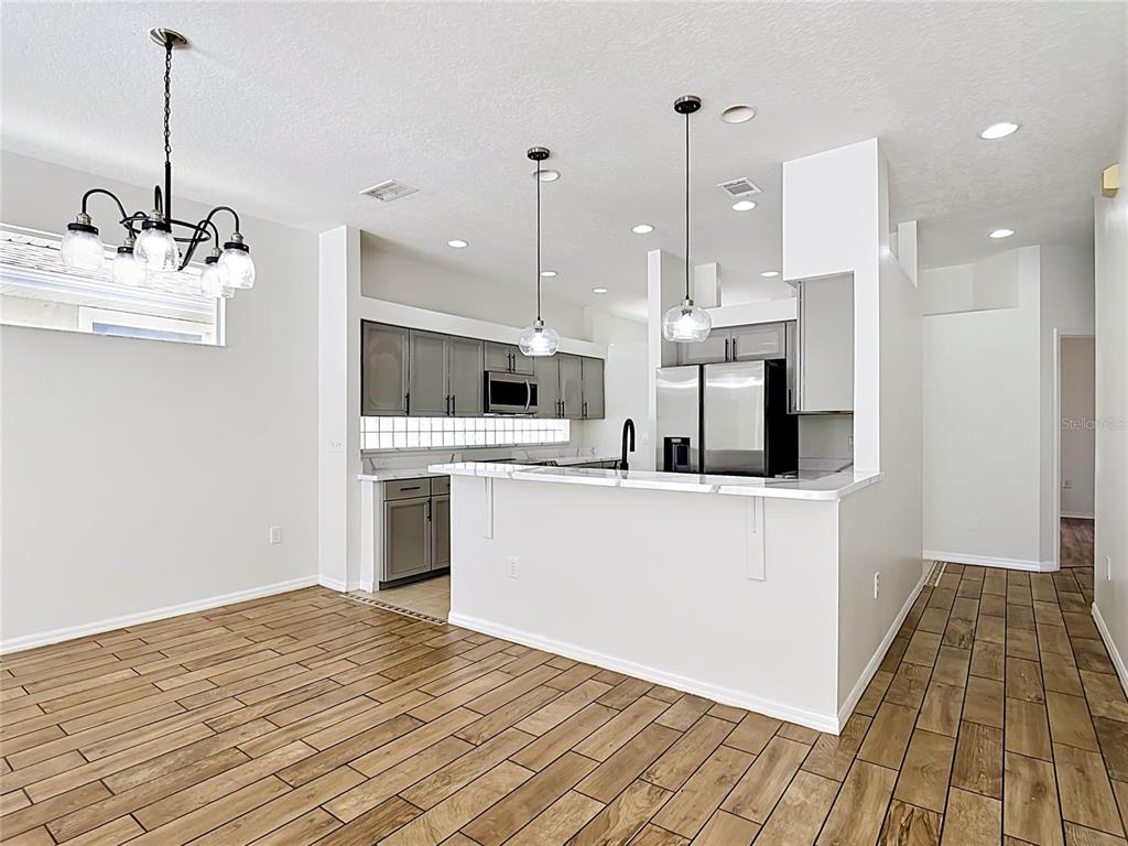 A kitchen with grey cabinets, a white breakfast bar, and wood-look tile flooring — 2944 SUNSET VISTA BOULEVARD, KISSIMMEE, FL