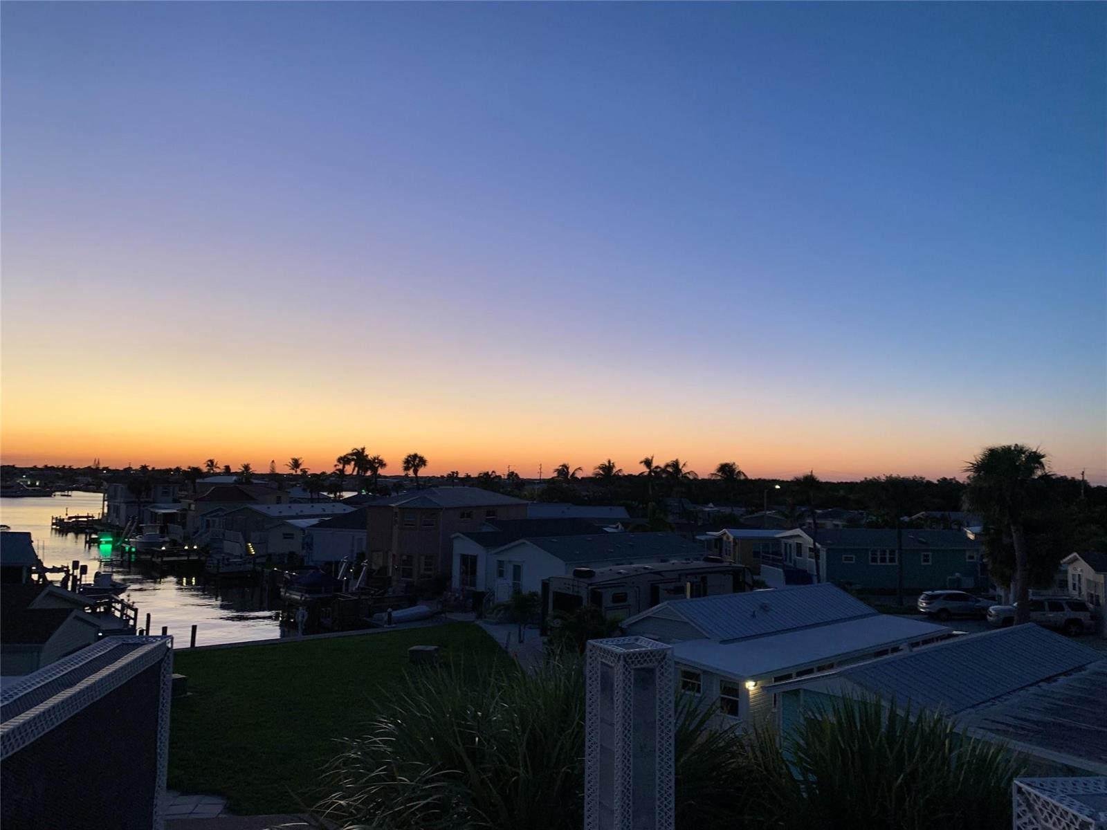 An elevated view of a coastal neighborhood at sunset with houses, boats, and palm trees — 2045 Nettles Boulevard, Jensen Beach FL 34957, JENSEN BEACH, FL