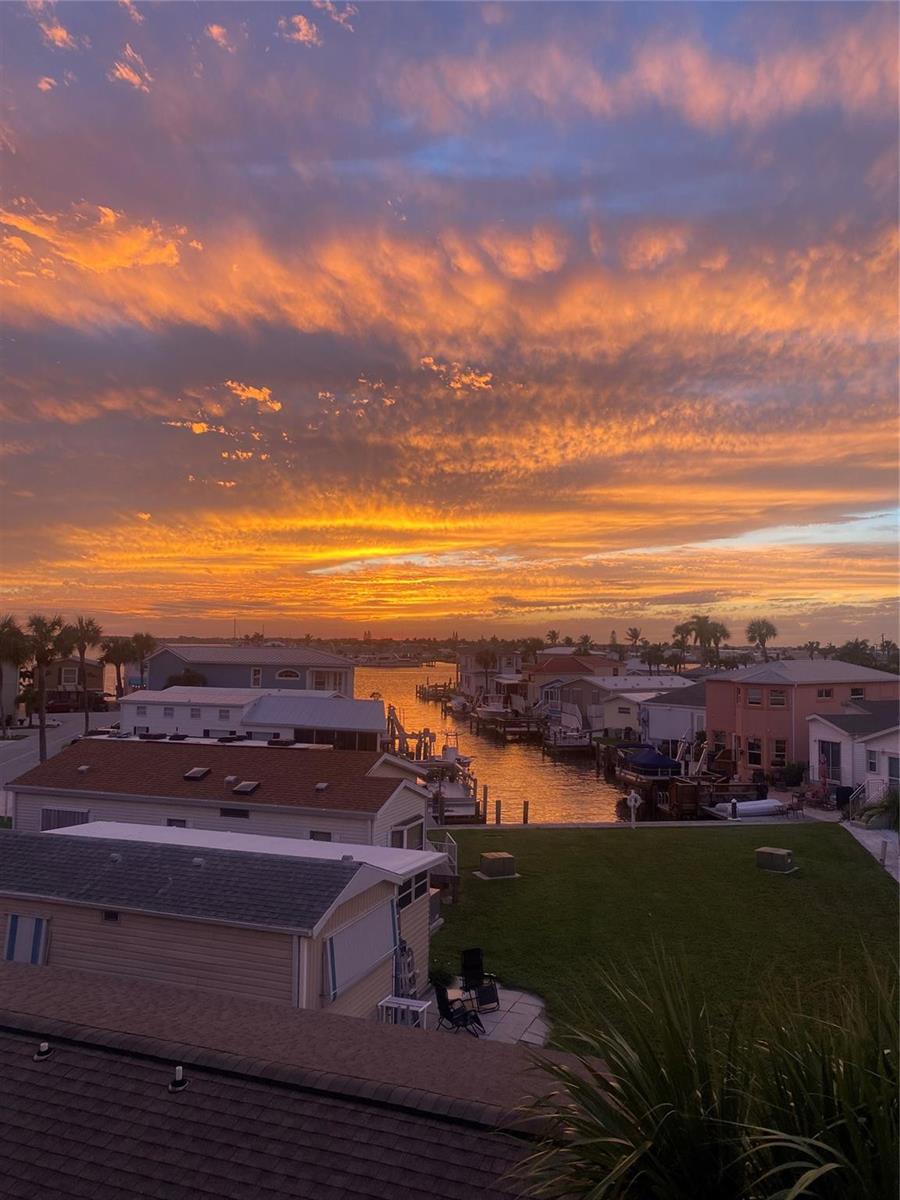 An elevated view of a canal-side neighborhood at sunset with houses and a grassy lawn — 2045 Nettles Boulevard, Jensen Beach FL 34957, JENSEN BEACH, FL