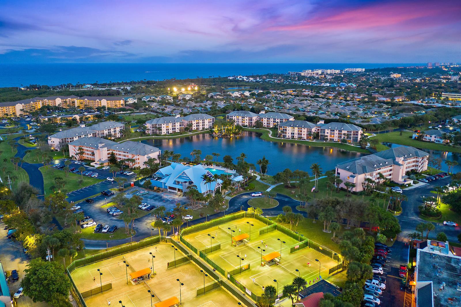 An aerial view shows a residential complex with a lake, tennis courts, and parking lots — 353 S Us Highway 1 # A203, Jupiter FL 33477, JUPITER, FL