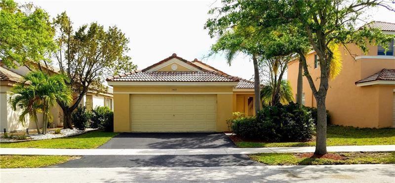 A single-story house with a tan stucco exterior, a two-car garage, and a tiled roof — 1409 Sabal Trail, Weston FL 33327, WESTON, FL