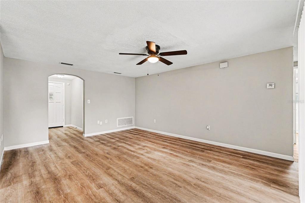 An empty room with light gray walls, wood-look flooring, and a ceiling fan — 7030 INGLESIDE DRIVE, PORT RICHEY, FL