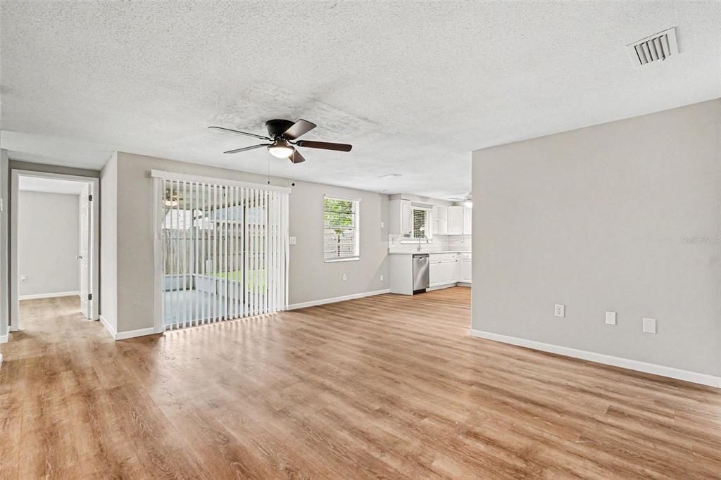 A living room with wood-look flooring, a ceiling fan, and a sliding glass door — 7030 INGLESIDE DRIVE, PORT RICHEY, FL