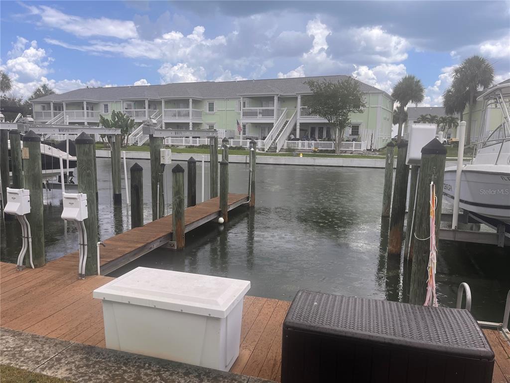 A wooden dock with storage boxes extends into a canal facing a multi-story apartment building — 0 BEACH DRIVE SE UNIT 151SS, ST PETERSBURG, FL