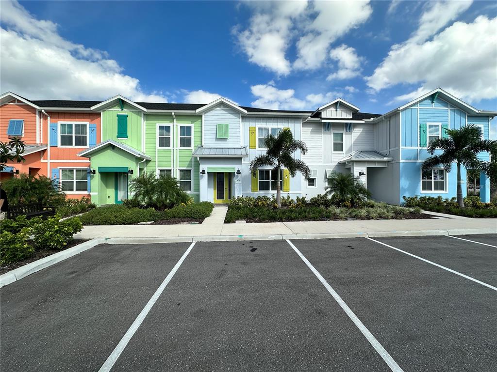 A row of colorful, multi-story townhomes features a parking lot in the foreground — 2976 ON THE ROCKS POINT, KISSIMMEE, FL