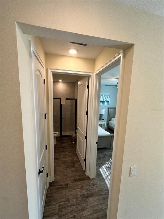 A hallway leads to a bathroom with a glass shower and an adjacent bedroom — 2976 ON THE ROCKS POINT, KISSIMMEE, FL