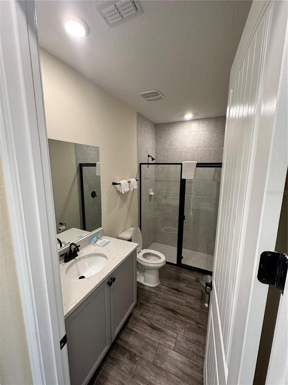 A bathroom features a gray vanity, a walk-in glass shower, and wood-look tile flooring — 2976 ON THE ROCKS POINT, KISSIMMEE, FL