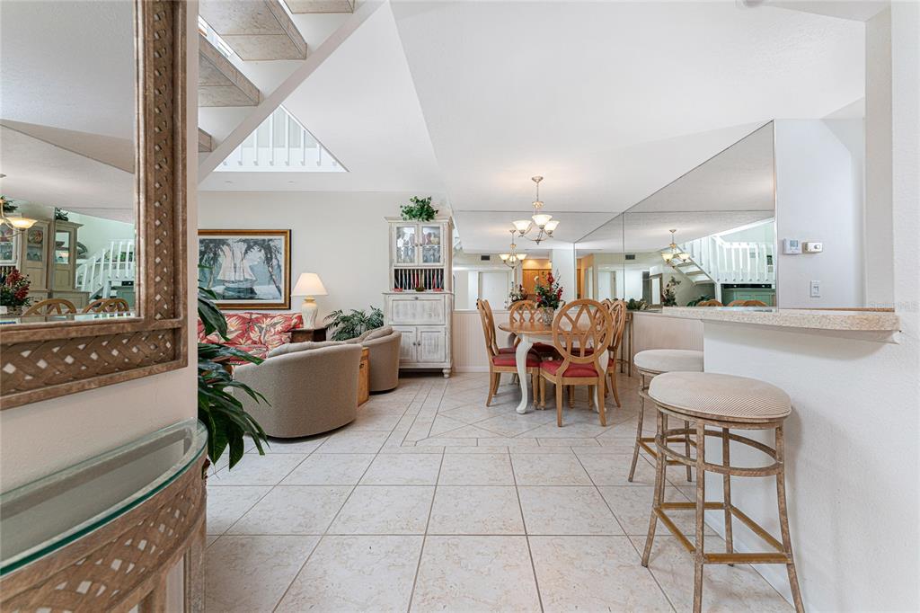 A living and dining area features tile flooring, a staircase, and a breakfast bar — 2950 N BEACH ROAD UNIT B522, ENGLEWOOD, FL