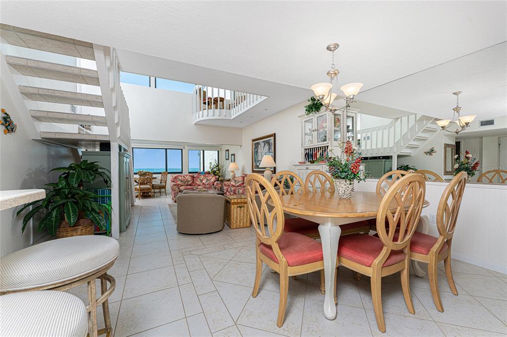 A dining area with a wooden table and chairs sits before a living room overlooking water — 2950 N BEACH ROAD UNIT B522, ENGLEWOOD, FL