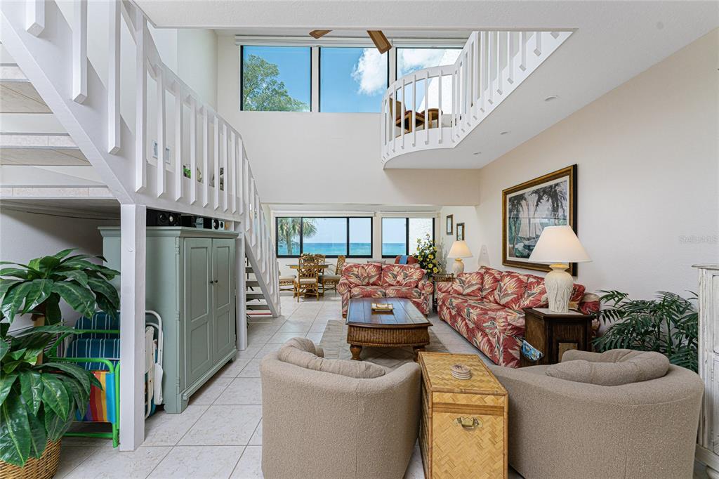 A bright living room features a vaulted ceiling, a lofted walkway, and ocean views — 2950 N BEACH ROAD UNIT B522, ENGLEWOOD, FL