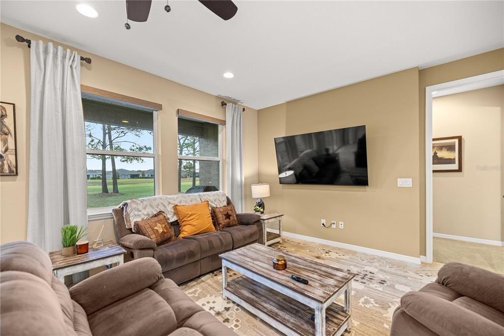 A living room features brown sofas, a wooden coffee table, and a wall-mounted television — 5471 NW 34TH STREET, OCALA, FL