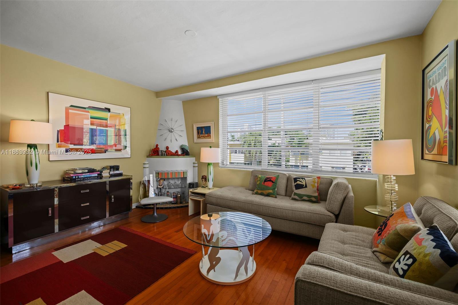 A living room features hardwood floors, a corner fireplace, two sofas, and colorful wall art — 1525 Meridian Ave # 202, Miami Beach FL 33139, MIAMI BEACH, FL