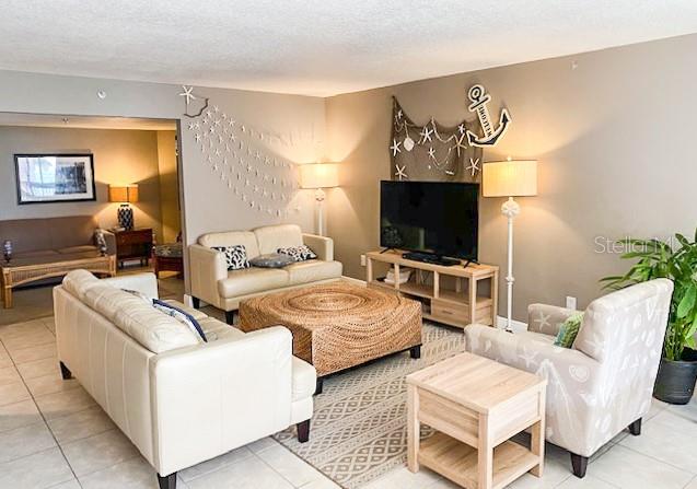 A coastal-themed living room features two beige sofas, an armchair, and a large woven ottoman — 5611 GULF OF MEXICO DRIVE UNIT 5, LONGBOAT KEY, FL