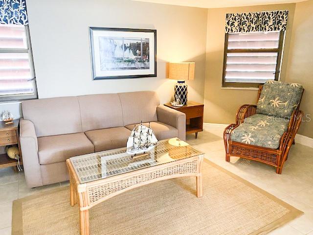 A living room features a beige sofa, a wicker coffee table, and a patterned armchair — 5611 GULF OF MEXICO DRIVE UNIT 5, LONGBOAT KEY, FL