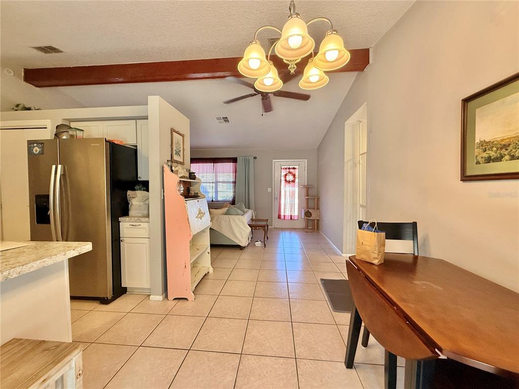 A dining area with a wooden table leads into a living room with tile floors — 12258 FOOTHILL STREET, SPRING HILL, FL