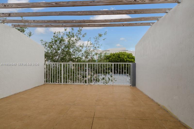 An outdoor rooftop terrace features tan tile flooring, white side walls, and a wooden pergola — 2734 Bird Ave # 310, Miami FL 33133, MIAMI, FL