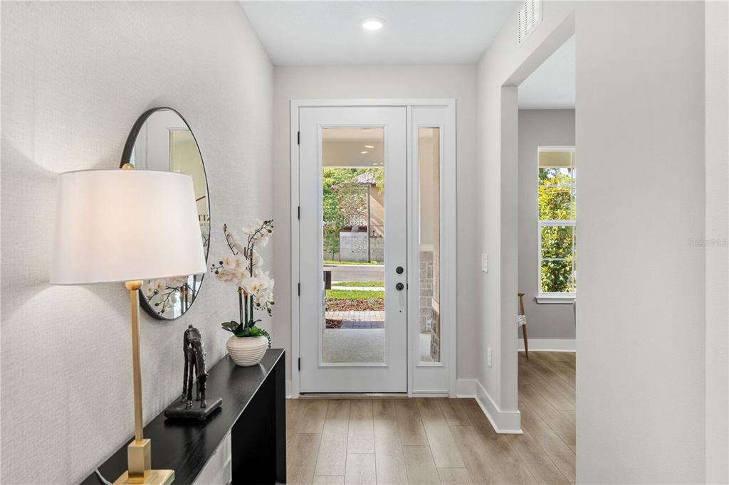 A bright entryway features a white front door, light wood flooring, and a console table — 2363 HUANIER COURT, APOPKA, FL