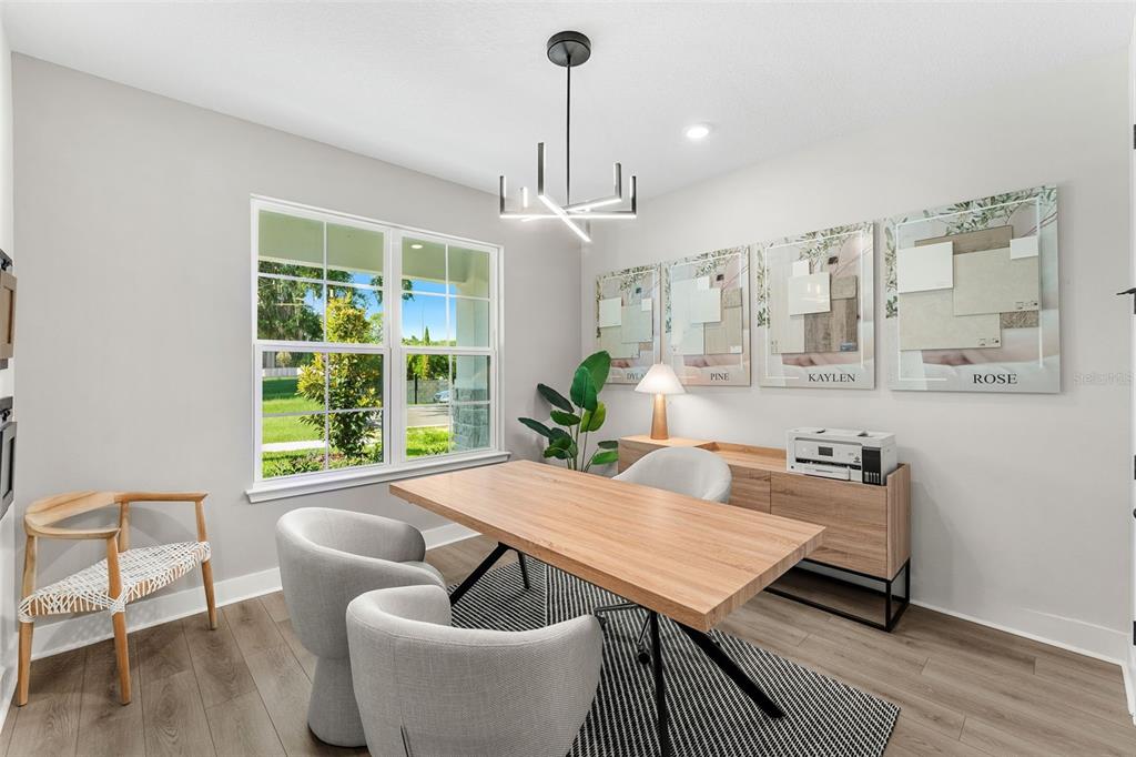 A home office features a wooden desk, gray chairs, a modern chandelier, and wall-mounted decor — 2363 HUANIER COURT, APOPKA, FL